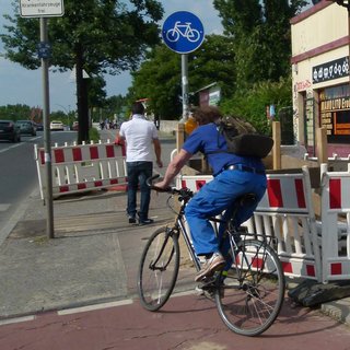 Fußgänger muss Radweg benutzen und ein Radfahrer biegt ein.